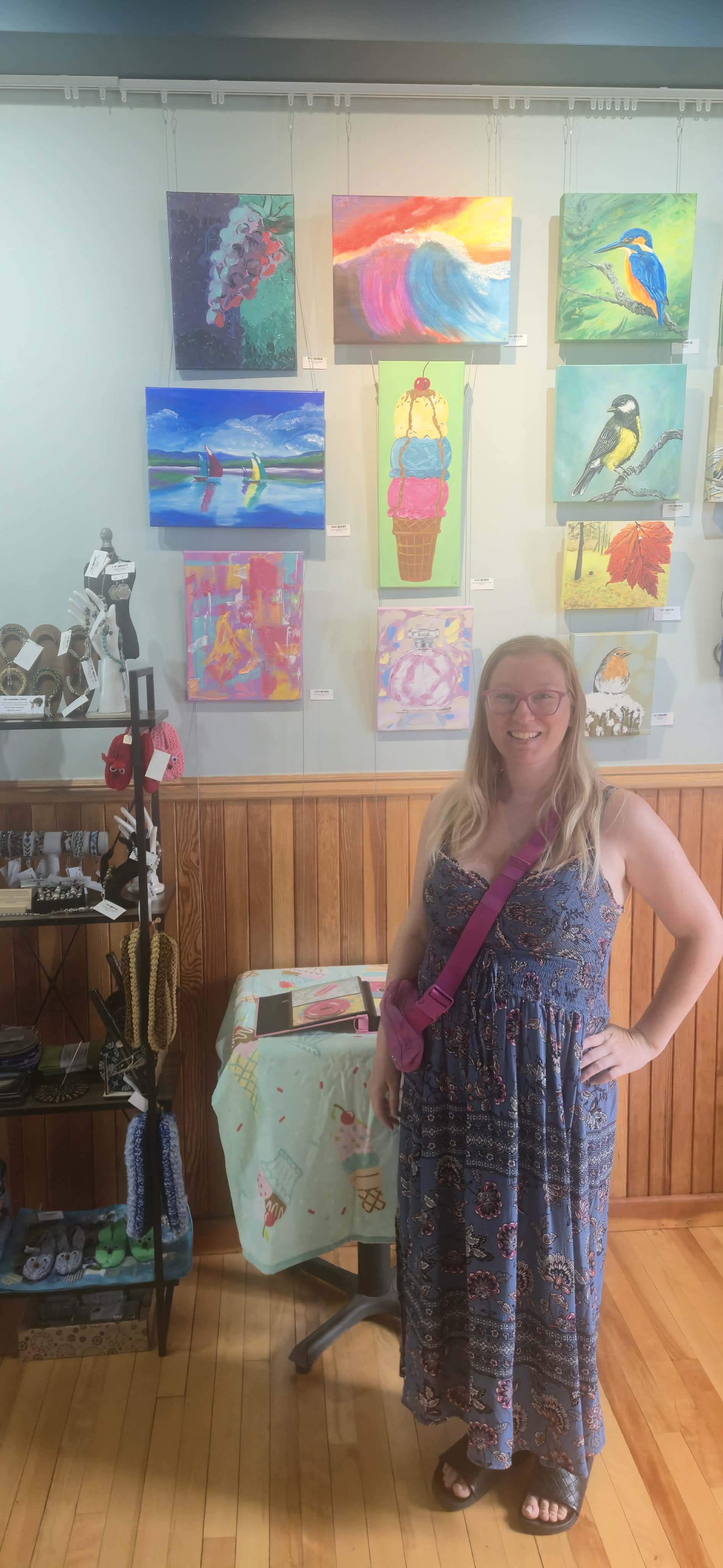 Jacqueline standing beside a large display of her colourful paintings